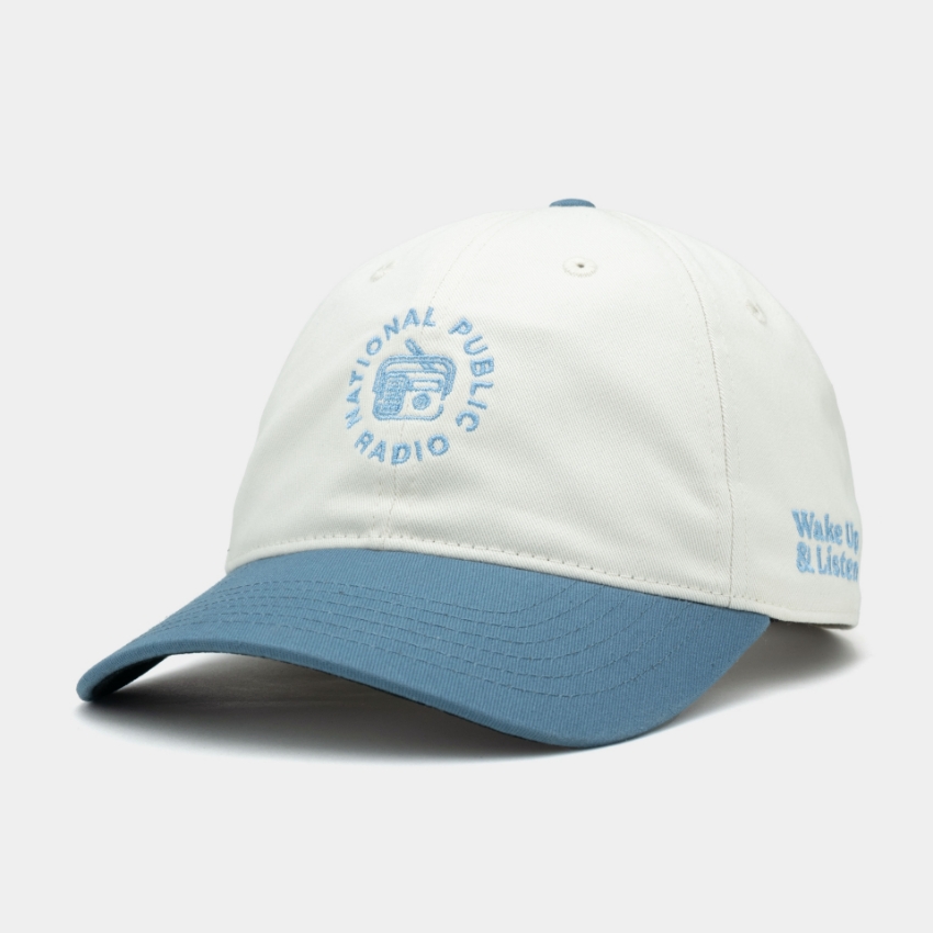 Blue and grey hat with the NPR Wake Up & Listen design embroidered on the front